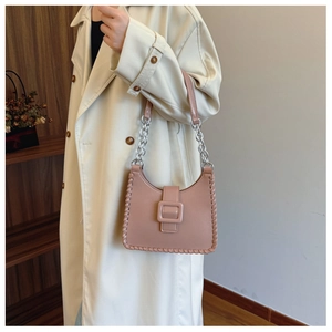 Detail of hand-woven stitching and silver chain strap on a pink leather shoulder bag