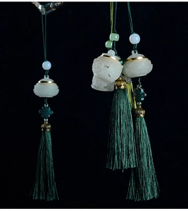Detail of hollow carved jade rabbit pendant with dark green tassel on black background