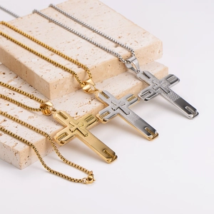 Three cross necklaces in gold, silver, and two-tone on a travertine stone display