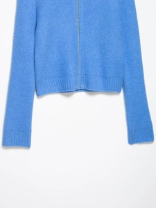 Detail of light blue knit cardigan with metal zipper and fine ribbed cuff texture