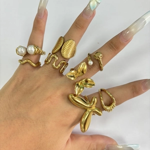 Detail of gold-plated wavy rings with pearls and floral motifs worn on fingers