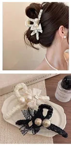 Détail d'une pince à cheveux élégante avec nœud en dentelle, perles et logo métal