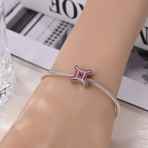 Close-up of Gemini constellation charm with pink enamel and crystals on silver bracelet