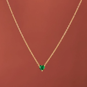 18k gold plated heart necklace with green birthstone pendant on red brown background