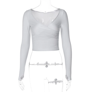 Détail du haut blanc à manches longues avec décolleté en V profond, design croisé et passe-pouces