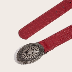 Red crocodile texture leather belt with a vintage engraved silver oval buckle on beige background