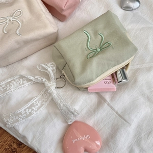 Detail of canvas makeup bag showing ribbon embroidery and spacious layered interior