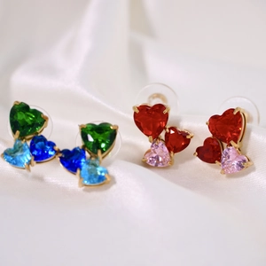 Macro shot of heart-shaped earrings with colorful faceted crystals on gold base