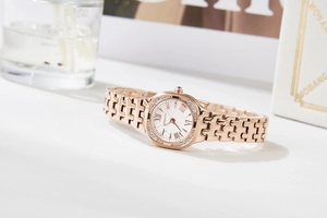 Detail of rose gold watch with diamond bezel and roman numerals in luxury setting