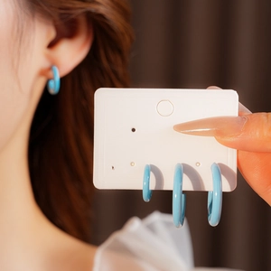 Detail view of 4-piece blue C-shaped drop oil earrings set displayed on a card and on ear
