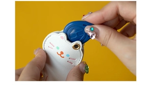 Détail d'un badge bleu inséré dans un étui de protection en cuir blanc en forme de chat