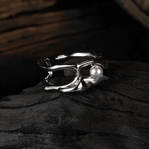 Macro shot of silver irregular lines ring with white pearl on a dark charcoal base