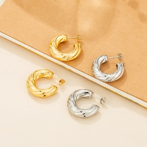 Close-up of gold and silver twisted C-shaped earrings with fine spiral texture details