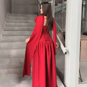 Back detail of red backless maxi dress featuring criss-cross lace-up design and long cape