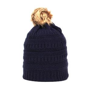 Detailed knit texture and pom-pom of a thick navy blue winter beanie for adults