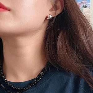 Orecchini curvi in argento 925 e collana di perline nere indossati da una modella
