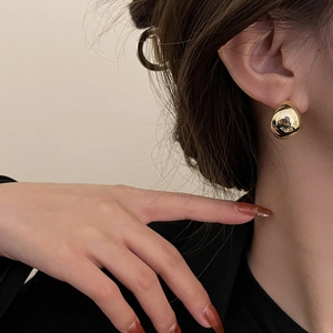 Close-up of minimalist gold teardrop earrings worn by a model for an elegant look