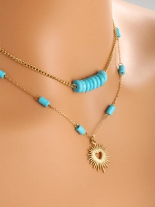 Detail of layered gold-plated stainless steel necklace with turquoise beads and sun heart pendant