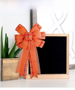 Detail of harvest pumpkin orange bow with tartan plaid ribbon on wooden background