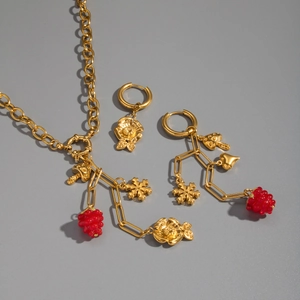 Flat lay of 18K gold plated fruit jewelry set featuring berry and mushroom charms