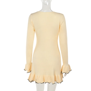 Detalle de vestido de punto amarillo claro con bordes negros en contraste en dobladillo y mangas