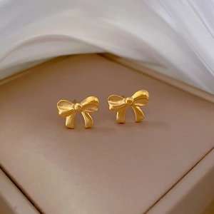 Elegant gold bow-shaped titanium steel stud earrings on a premium silk and jewelry box base