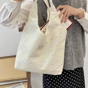 Detail of a knit tote bag with rainbow stripes and a woven brand label for a sweet style
