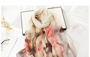 Detail view of lightweight floral silk scarf draped elegantly over a luxury gift box