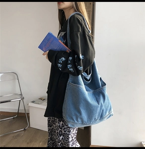 Detail view of large capacity washed blue denim tote bag with soft texture and front pocket