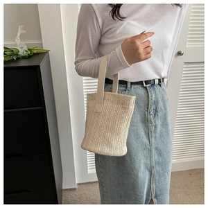 Close-up of beige woven straw bucket bag with textured handles for summer beach vacations