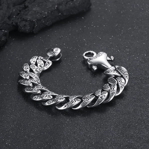 Macro detail of Egyptian hieroglyphs engraved on vintage punk steel cuban chain bracelet
