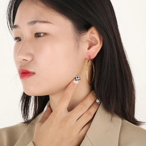 Primo piano di donna che indossa orecchini a cerchio minimalisti in acciaio dorato 18K