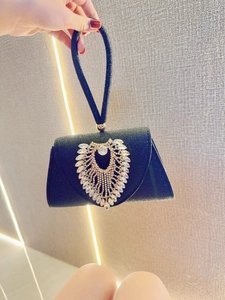 Macro view of black glitter evening bag featuring a large heart-shaped crystal buckle