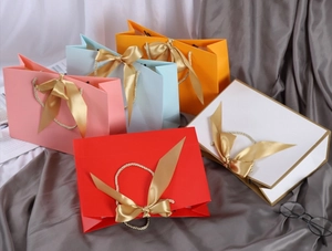 Detailed view of colorful gift bags featuring gold handles and silk ribbon bows