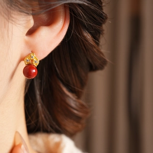 Close-up of vintage flower stud earring with red bead and crystal inlay on model