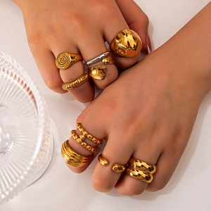 Golden irregular chunky rings set on model hands with glossy metallic finish and texture