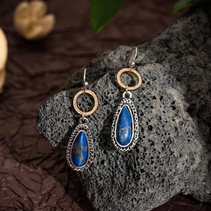 Detailed macro view of teardrop lapis lazuli earrings with vintage mixed metal textures