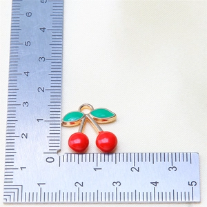 Macro detail of red and green enamel cherry fruit pendant for DIY jewelry making