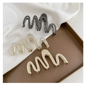 Close-up of wavy metal hair claws with rhinestones and pearls on a silk background
