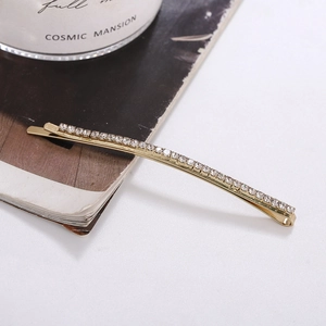 Detail of a minimalist gold hair clip with sparkling rhinestones in an elegant setting