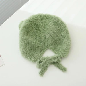 Close-up of fluffy green plush frog hat for babies with soft tie-up bow detail