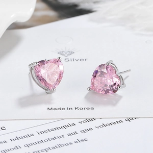 Macro view of pink heart-shaped cubic zirconia stud earrings with silver three-prong setting