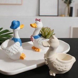 Detail view of mini duck succulent planters and candle holders in a ceramic tray