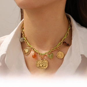Detail of bohemian gold chain necklace with heart and stone charms on white shirt