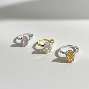 Macro detail of three silver and gold rings with oval cut pink, white, and yellow zircons
