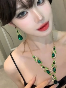 Close-up of elegant emerald green teardrop necklace and earring set on a female model