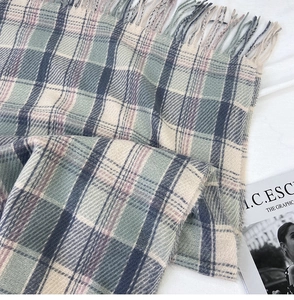 Detailed view of the soft plaid pattern fabric and tassel edge on winter scarf