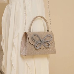 Close-up of sparkling gold clutch with rhinestone bow and silver chain strap details