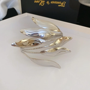 Detailed view of silver multi-layer leaf bangle on a white tray with a black gift box