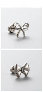 Close-up of titanium steel bow earrings with zircon stones and polished silver finish